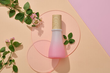 A pink jar with wooden cap placed on pink round acrylic sheets with Lantana camara flowers....