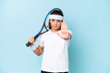 Young tennis player woman isolated on blue background making stop gesture