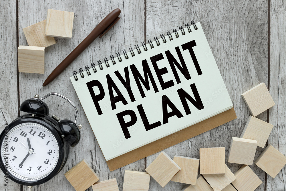 Poster payment plan text on an open notepad on the table. text on wooden blocks