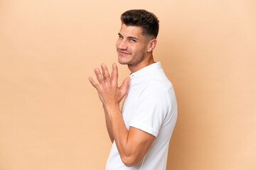 Young caucasian man isolated on beige background scheming something