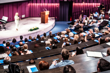 Business and entrepreneurship symposium. Female speaker giving a talk at business meeting. Audience...