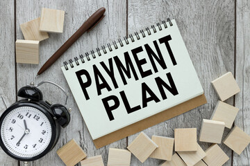 PAYMENT PLAN text on an open notepad on the table. text on wooden blocks