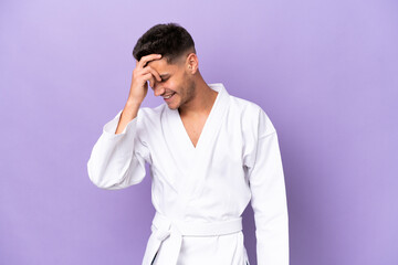 Young caucasian man doing karate isolated on purple background laughing