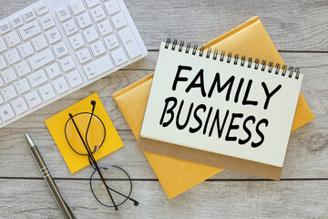 FAMILY BUSINESS notepad with spring on yellow notepad on wooden table