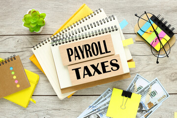 payroll taxes . two wooden blocks with text on a notebook with a spring. bright stickers - obrazy, fototapety, plakaty