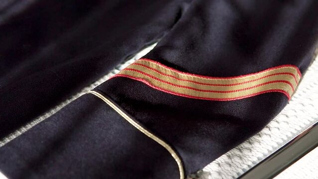 Slow rotating shot of a military man's outfit with golden stripes on the arm