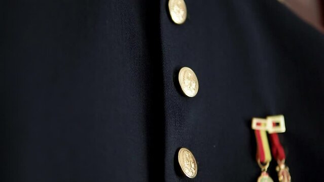 Slow tilting shot of a military outfit with golden pins hanging for a wedding