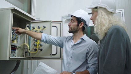 Electrician man worker and woman factory manager working and checking electrical control panel in industrial factory