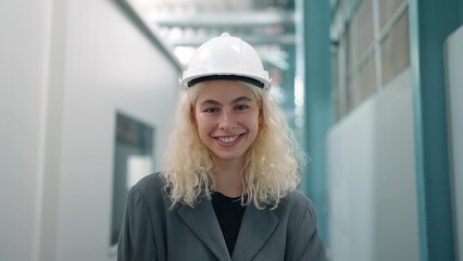 Smiling portrait of beautiful industrial engineer woman in white hard hat stand with confident and looking at camera