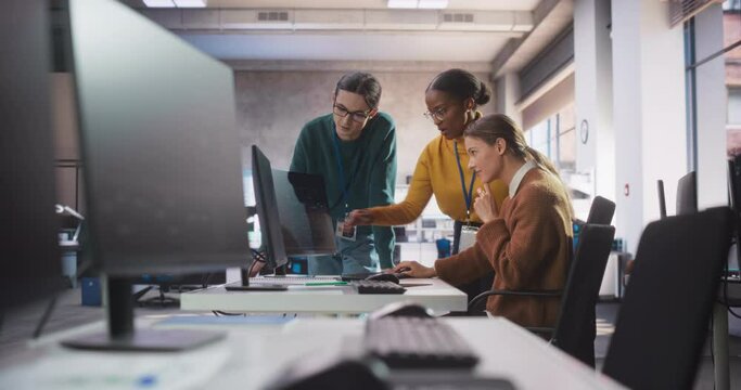 Diverse Multiethnic Team of Students Sitting Together in Computer Class, Collaborating on a School Project. Young Software Developers Talking About Creating an Online Shopping Mobile Application