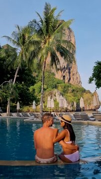 couple of men and women at a swimming pool at a luxury resort in Thailand. Luxury pool with chairs and parasols at Railay Beach Krabi