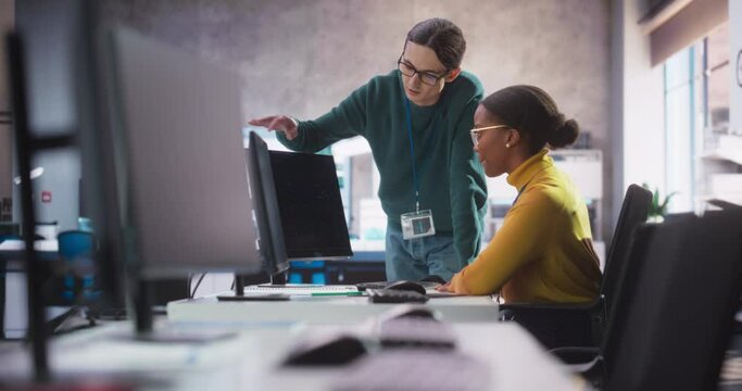 Two Diverse Young Professionals Having a Conversation in Office, Working With a Work Assignment on a Computer. Young Colleagues Talking, Thinking About Finishing a Software Development Project