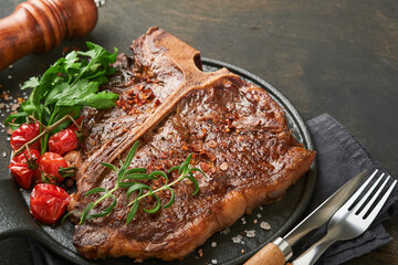 Steaks T-bone. Sliced beef grilled T-bone or porterhouse meat steak with spices rosemary and pepper on black marble board on old wooden background. Top view. Mock up.