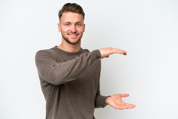 Young blonde caucasian man isolated on white background holding copyspace to insert an ad