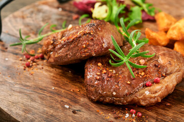 Steaks. Sliced grilled meat steak New York, Ribeye or Chuck roll with with garnished with salad and french fries on black marble board on old wooden background. Top view. Mock up.