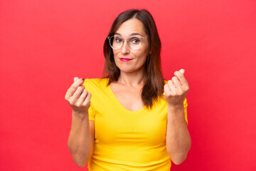 Middle-aged caucasian woman isolated on red background making money gesture
