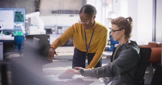 African Female Manager Having a Conversation with Young Intern Specialist in a Creative Agency, Collaborating on a Technology Project. Diverse Young Professionals Preparing for Software Presentation