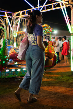 Woman smiling walking around in a cambodian amusement park with neon lights and people in the background