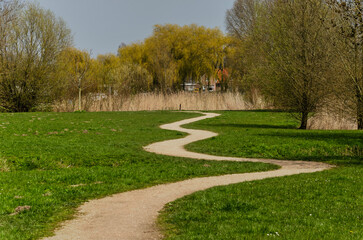 Sandy footpath meandering between grass and trees in Zuidelijk Randpark (Southern Fringe Park) in Rotterdam, The Netherlands