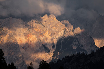 Sunset light on the dolomite  peaks mountain hidden by low clouds