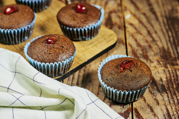 homemade chocolate nuts muffins decorated with candied cherry on wood table