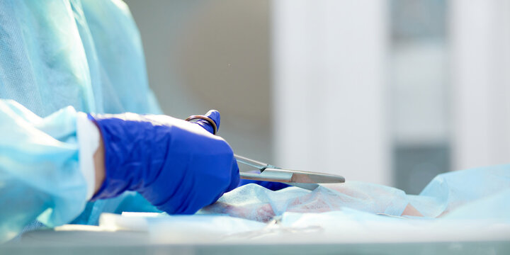 Close-up image of doctor's hands in protective gloves, surgeon leading operation, working with surgery tools, instruments. Concept of medicine, hospital, healthcare, treatment, profession