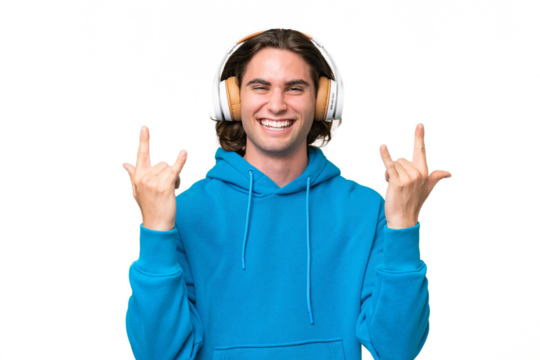 Young handsome man isolated on green chroma background listening music making rock gesture