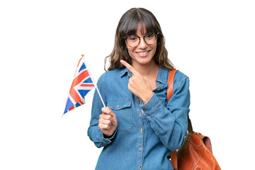 Young caucasian woman holding an United Kingdom flag over isolated background pointing to the side...