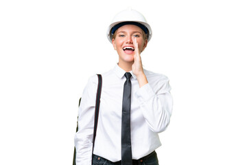 Young architect caucasian woman with helmet and holding blueprints over isolated background shouting with mouth wide open