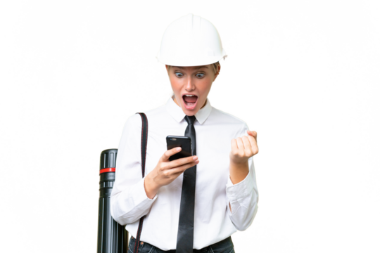 Young architect caucasian woman with helmet and holding blueprints over isolated background surprised and sending a message