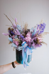 Woman's hand holding beautiful box full of purple, pink and blue dry flowers, vertical image - 597445045
