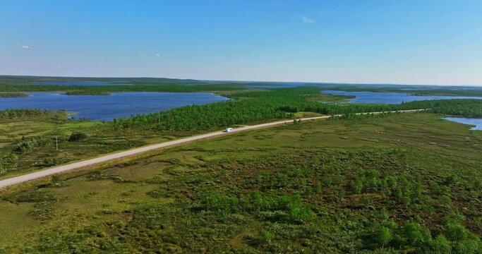 Aerial view tracking a caravanette driving in polar wetlands of North Finland