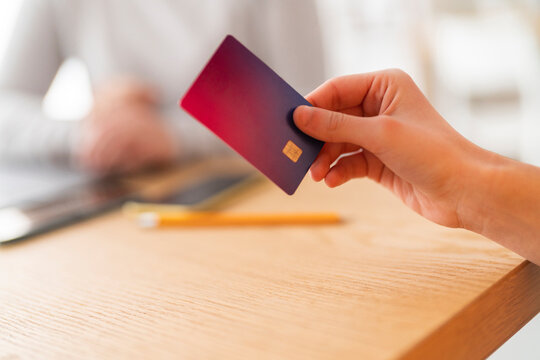 Crop anonymous female hand holding a credit card, out of focus background