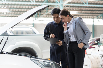 Car mechanic service and maintenance car engine concept. Male mechanic and female car owner customer discuss and checking car engine together during repair process in auto repair shop