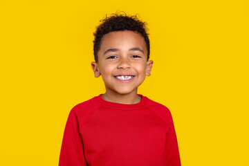 Portrait of cute African-American boy on yellow background
