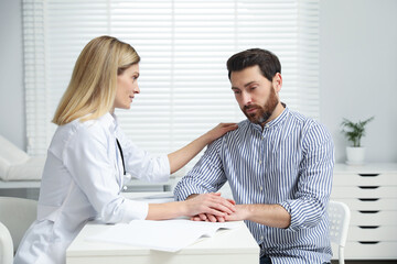 Doctor consulting patient at white table in clinic