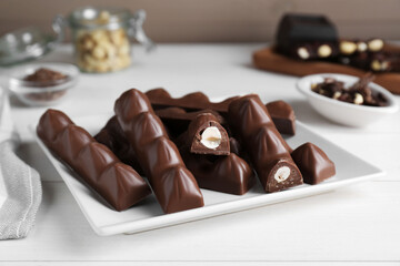 Tasty chocolate bars with nuts on white wooden table