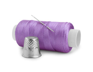Thimble and spool of violet sewing thread with needle isolated on white