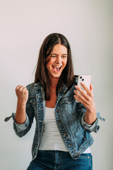 Euphoric woman looking at her smartphone and raising her fist.