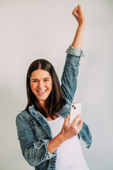 Euphoric woman looking at her smartphone and raising her arm.