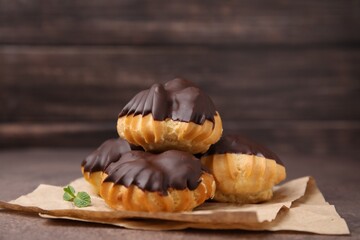 Delicious profiteroles with chocolate spread and mint on table, closeup