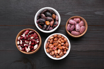 Different kinds of dry kidney beans on wooden table, flat lay