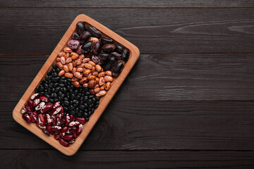 Plate with different kinds of dry kidney beans on wooden table, top view. Space for text