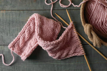 Soft pink woolen yarn, knitting and needles on wooden table, flat lay