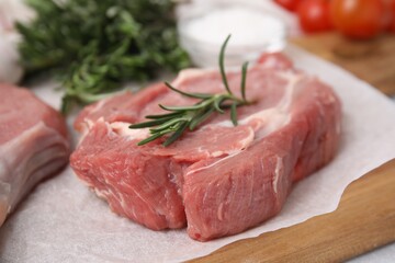 Fresh raw meat with rosemary on wooden board, closeup