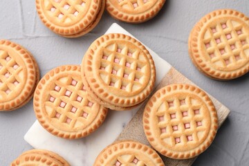 Tasty sandwich cookies with cream on light grey table, flat lay