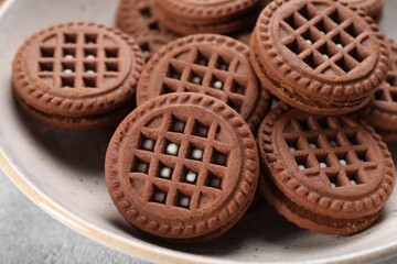 Tasty chocolate sandwich cookies with cream in bowl, closeup