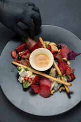 A glass of white wine sits on a table with a platter of meat cheese