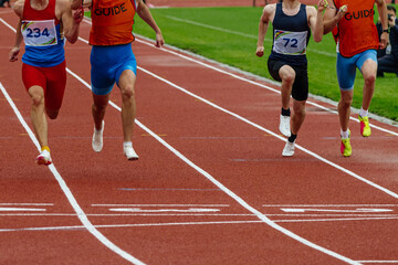 male blind para athletes runners with guides running finish line track stadium, summer para athletics championships