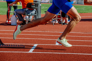 legs male athlete start running in starting blocks sprint race, summer athletics championships